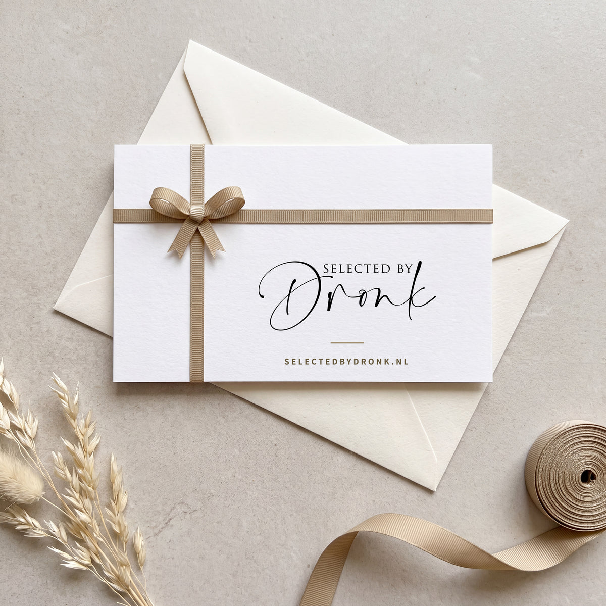 Cadeaubon van Selected by Dronk, witte kaart met zandgouden lint en strik op een crèmekleurige envelop