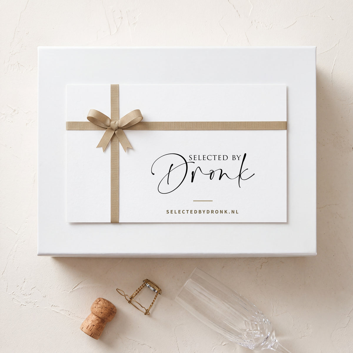 Cadeaubon van Selected by Dronk op een witte cadeaudoos, met een champagnekurk en een champagneglas