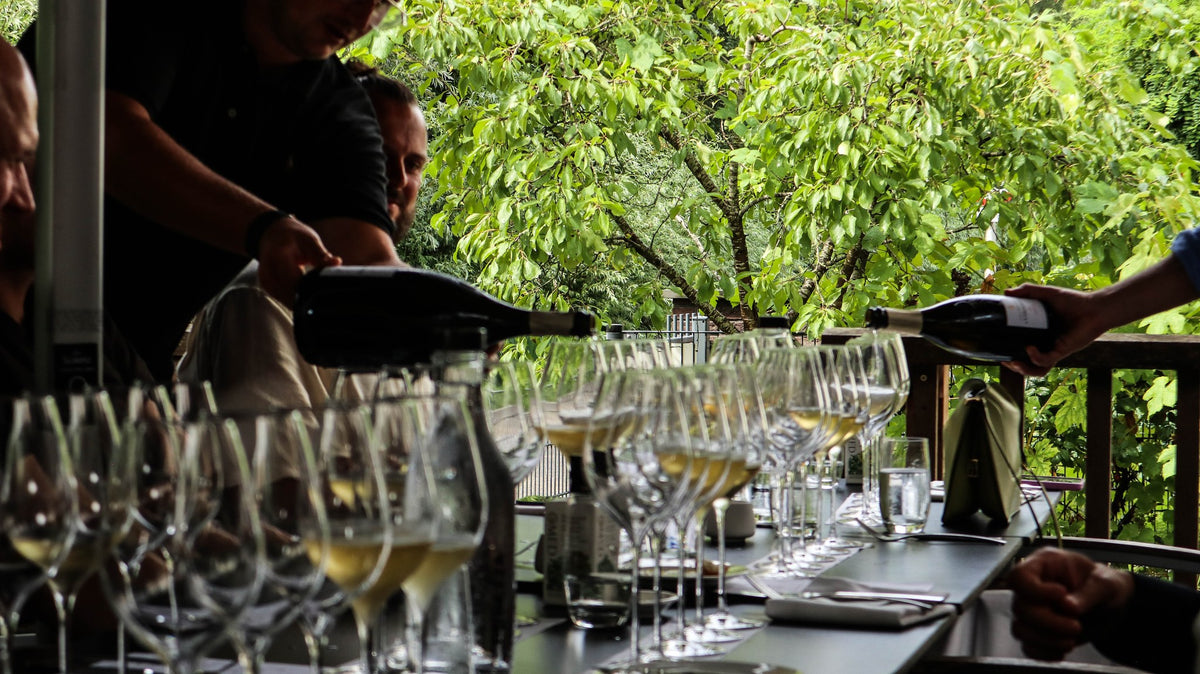Une longue table couverte de verres remplis, lors d'un déjeuner autour des millésimes organisé par Selected by Dronk