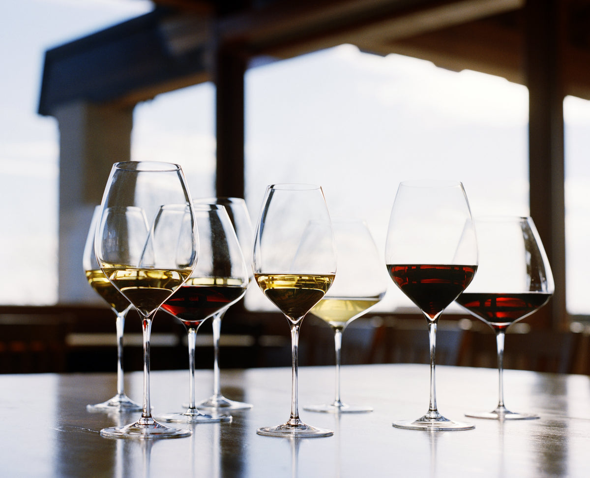 Verres à vin Italesse remplis de vin blanc et de vin rouge, sur une table à la lumière du jour