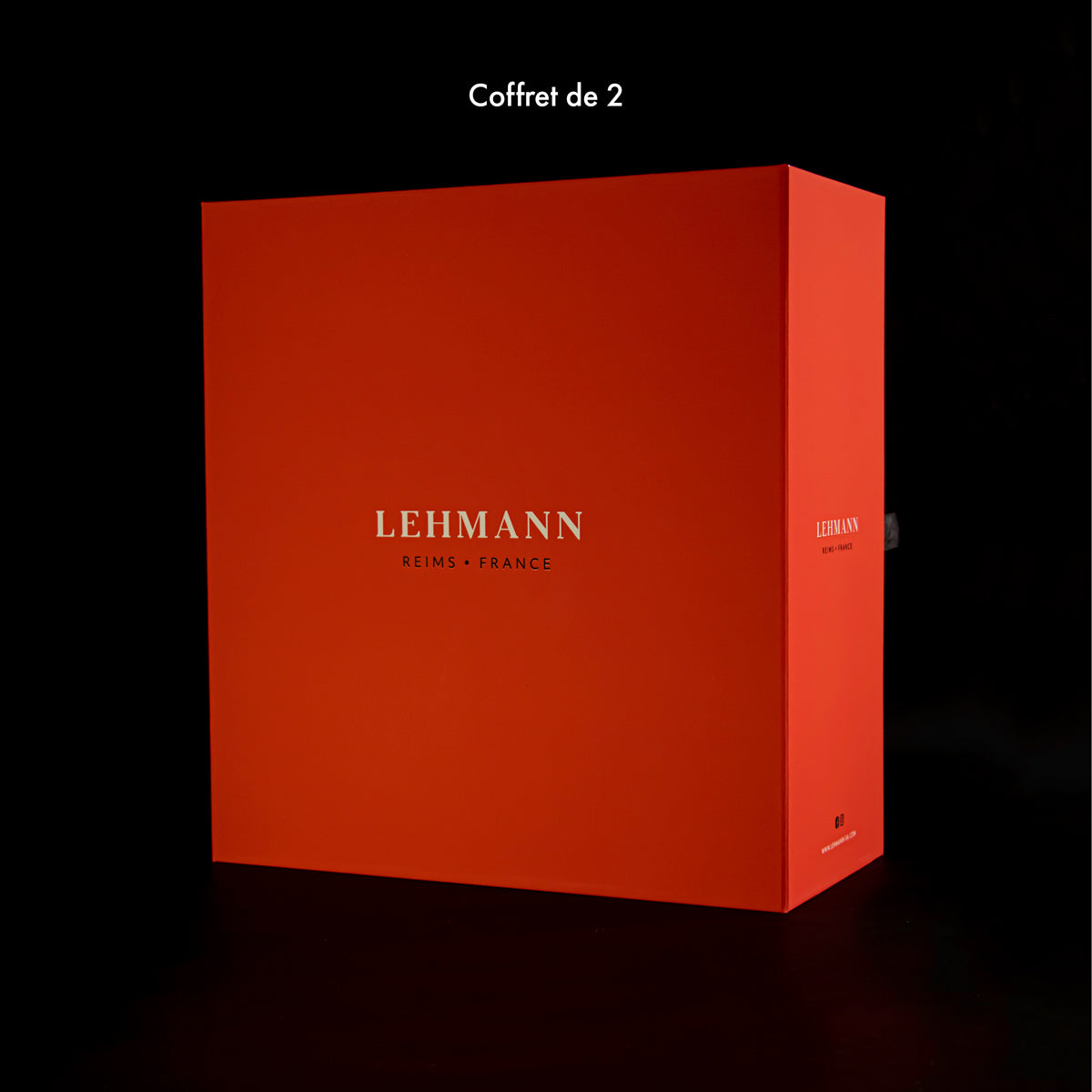 Gesloten cadeaudoos van Lehmann voor twee glazen, oranjerood met in lichte letters Lehmann Reims France, op een zwarte achtergrond met de tekst Coffret de 2